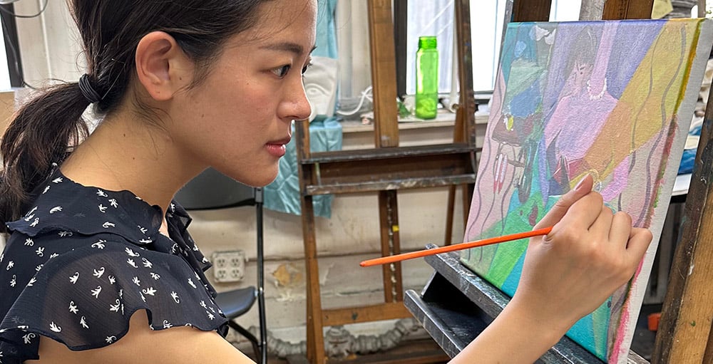 Adult student painting in a studio class with instructor guidance in New York