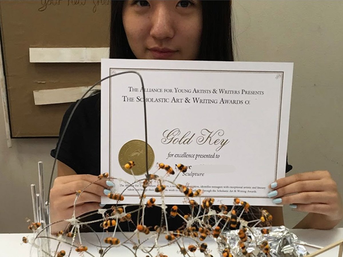 Student holding award certificate from art competition supporting college and art school portfolio